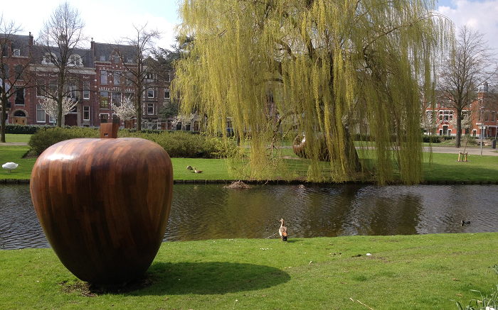 A photograph of a sculpture of an apple at the side of a river in Rotterdam, the Netherlands.