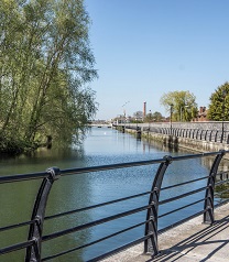 A photograph of a river (with a walkway and barrier alongside)